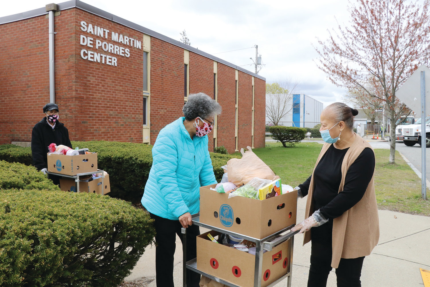 Director Linda A’Vant-Deishinni, at right, helps volunteers Cheryl Gray, left, and Gail Harris move boxes of food to their vehicle for distribution to homebound seniors in need.